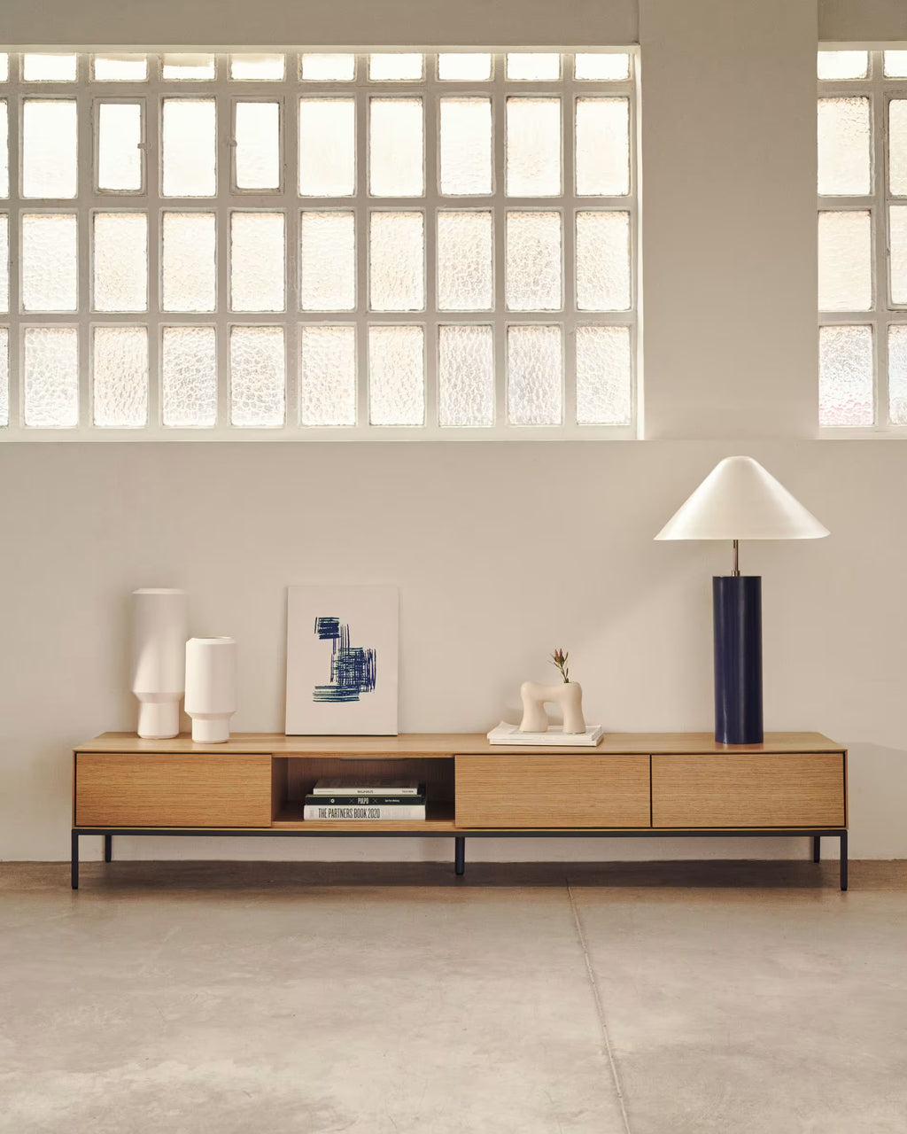 Modern living room with wooden console table, decorative items, and large windows.