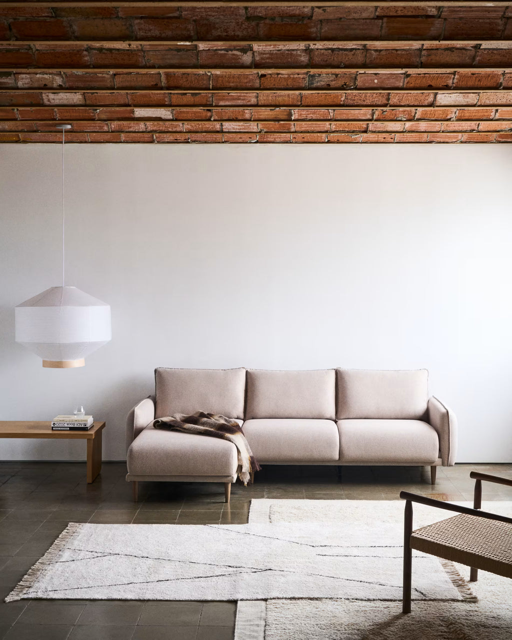 Modern living room with a beige sofa, wooden coffee table, and exposed brick wall.