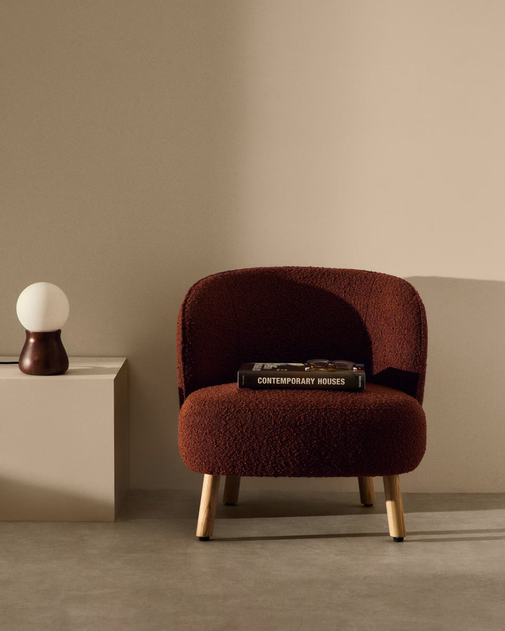 Brown armchair with a book on a beige surface against a beige wall
