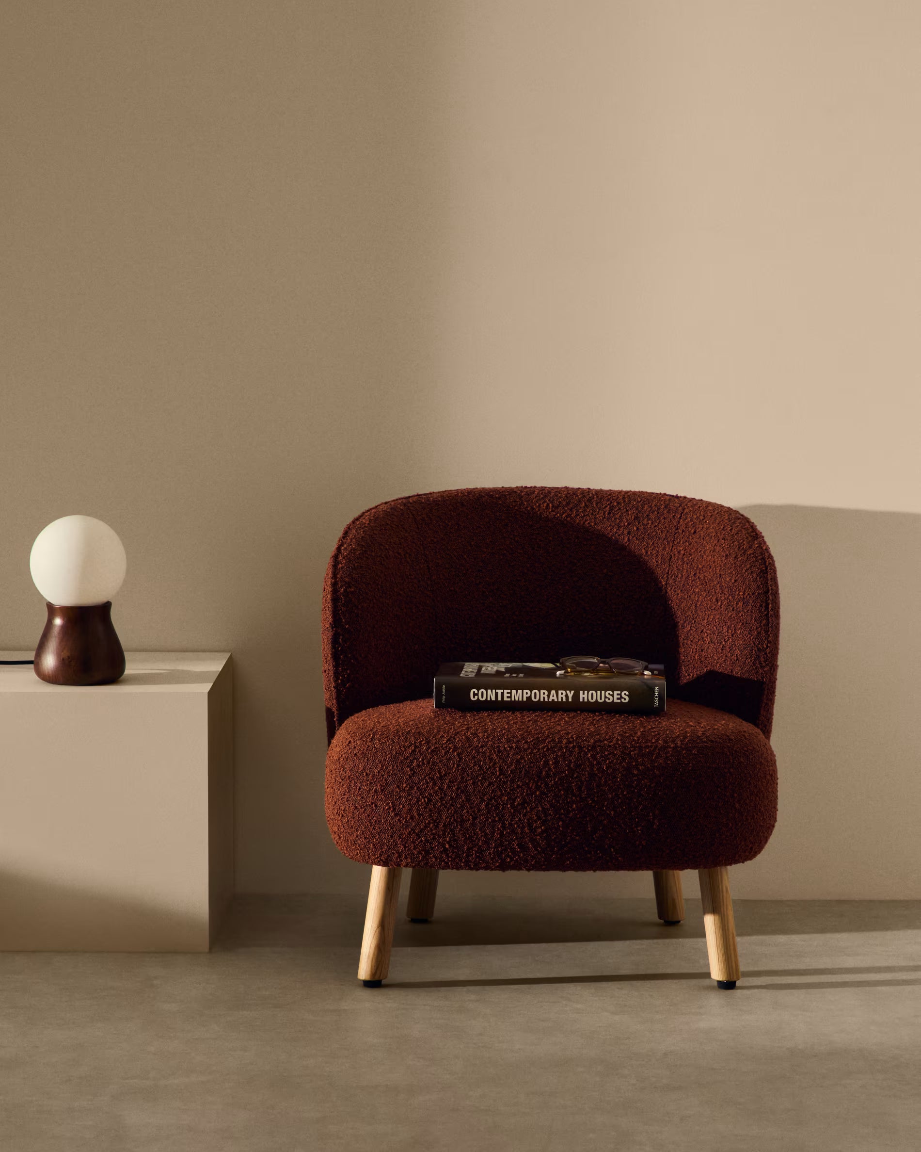 Brown armchair with a book on a beige surface against a beige wall