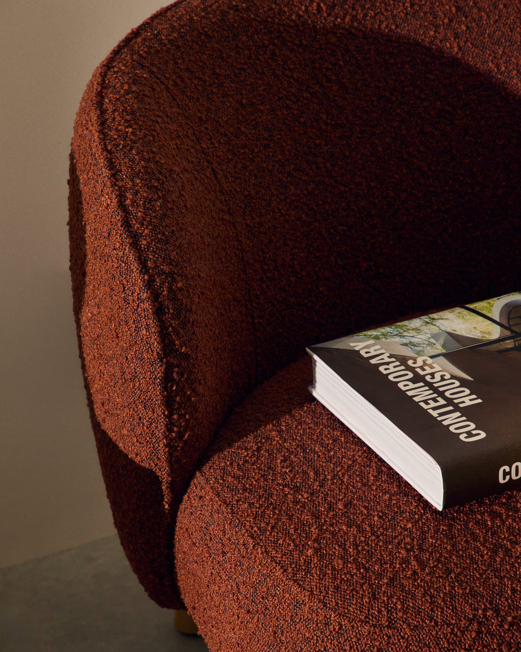 Brown textured armchair with a book on a neutral background