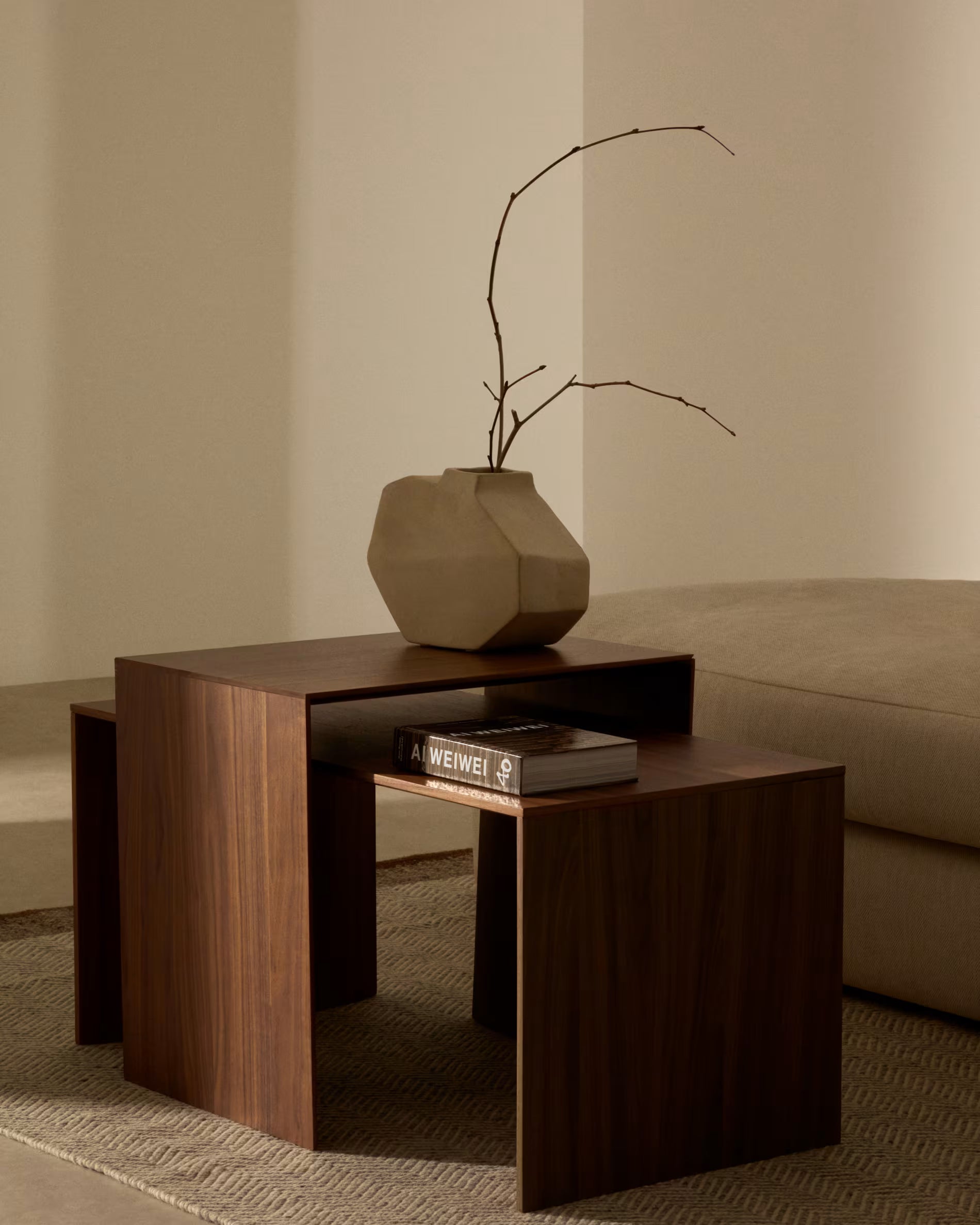 Wooden side table with a vase and books against a beige wall