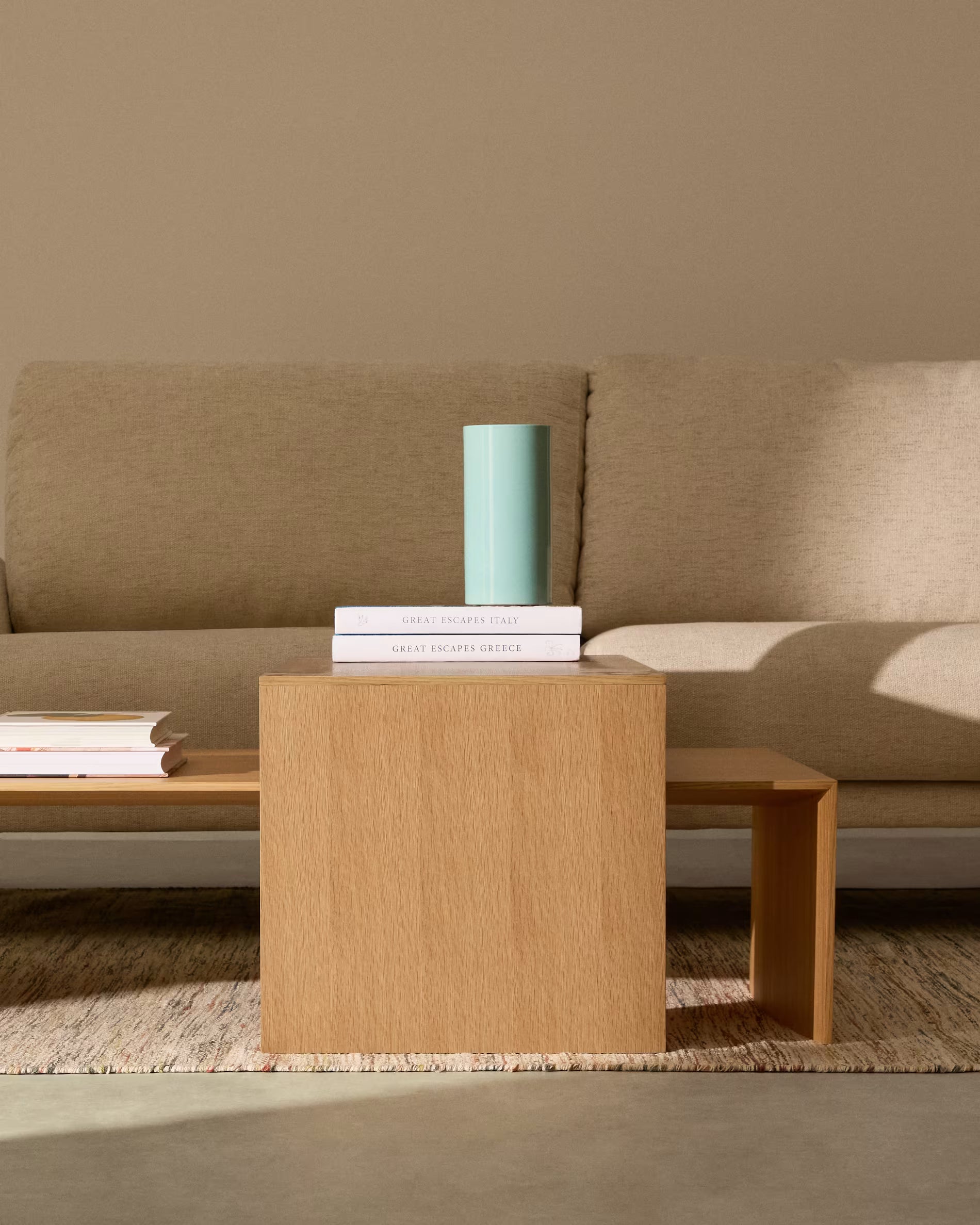 Beige sofa with a wooden coffee table and books on a neutral background