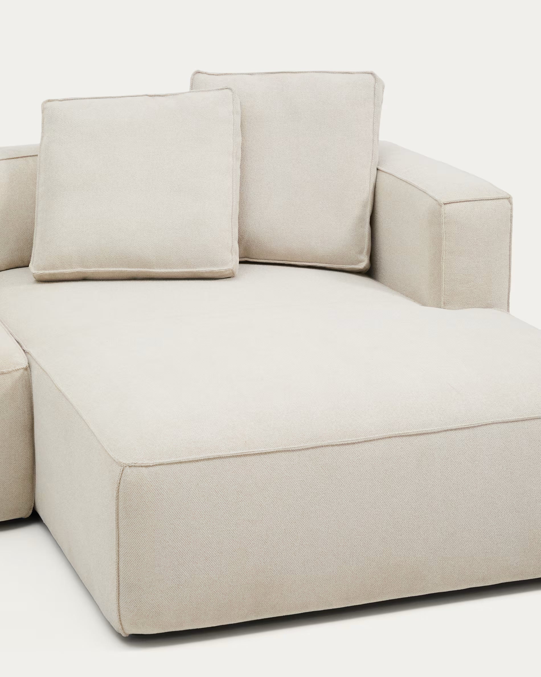 Beige sectional sofa with cushions on a white background