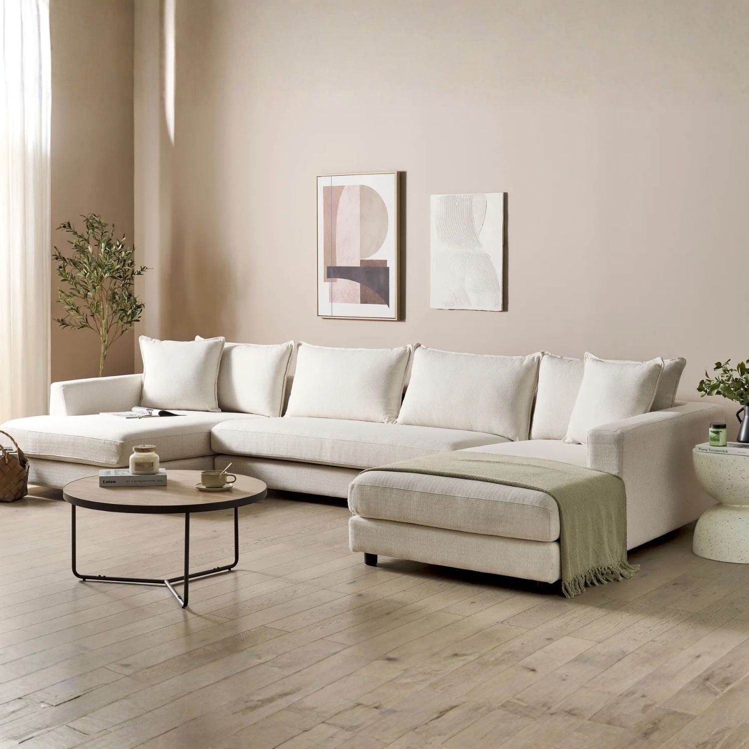 Modern living room with a white sectional sofa, coffee table, and abstract art on the wall.